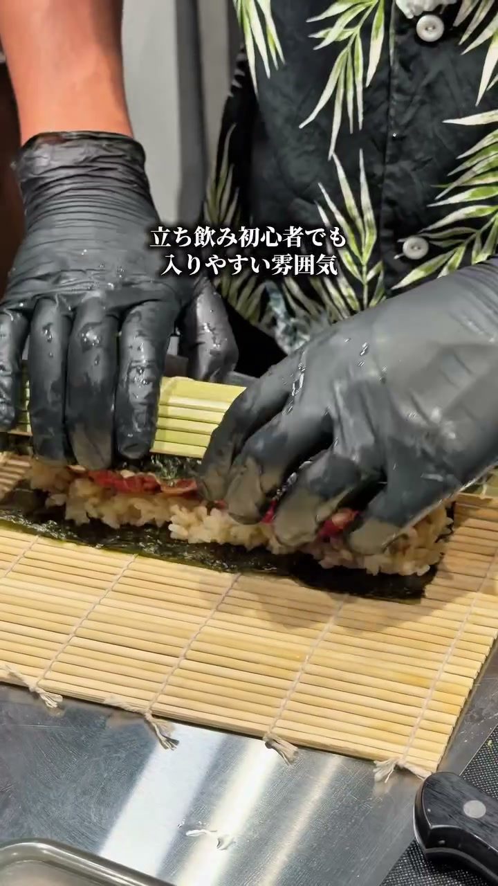 オープンキッチンで巻きすを使って巻き寿司を仕上げる手元