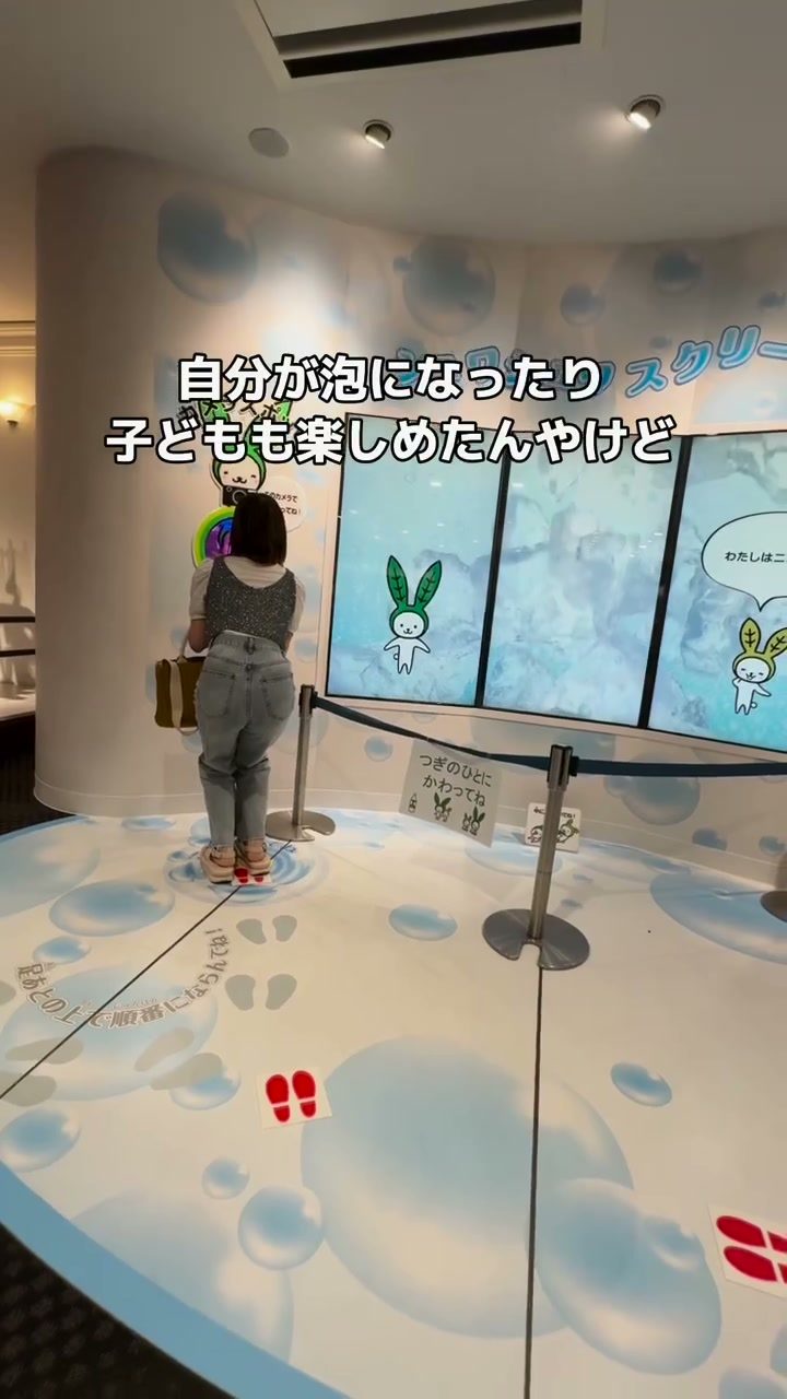 泡の映像が映るスクリーンの前で遊ぶ子どもの後ろ姿