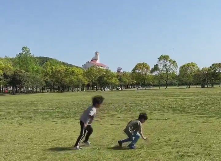 しあわせの村の広い芝生広場で走り回る子どもたち