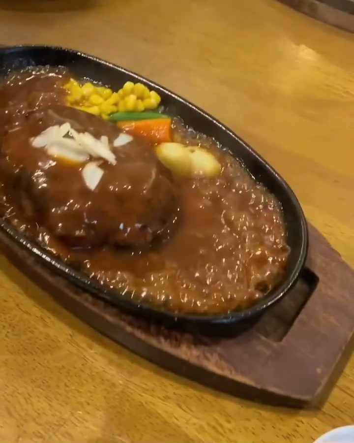木の台にのせた鉄板で湯気を立てるハンバーグとコーン