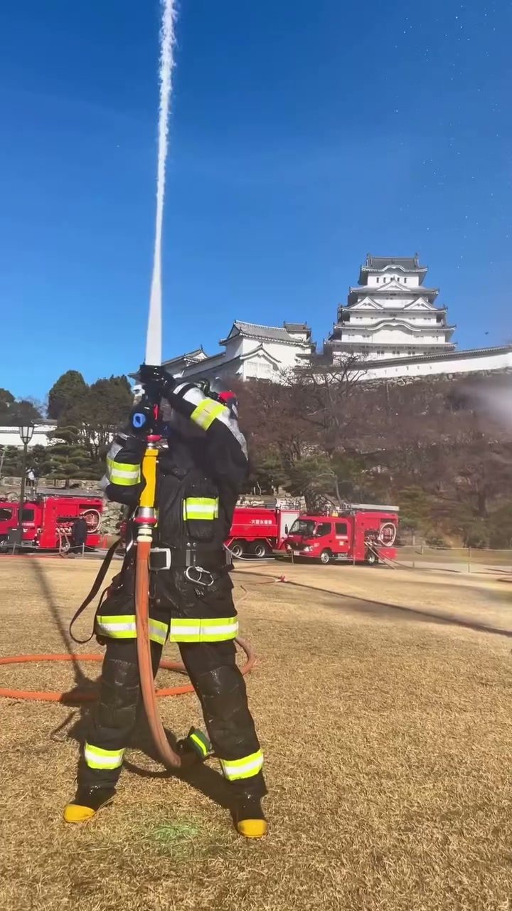 姫路城を背に空高く放水する消防隊員