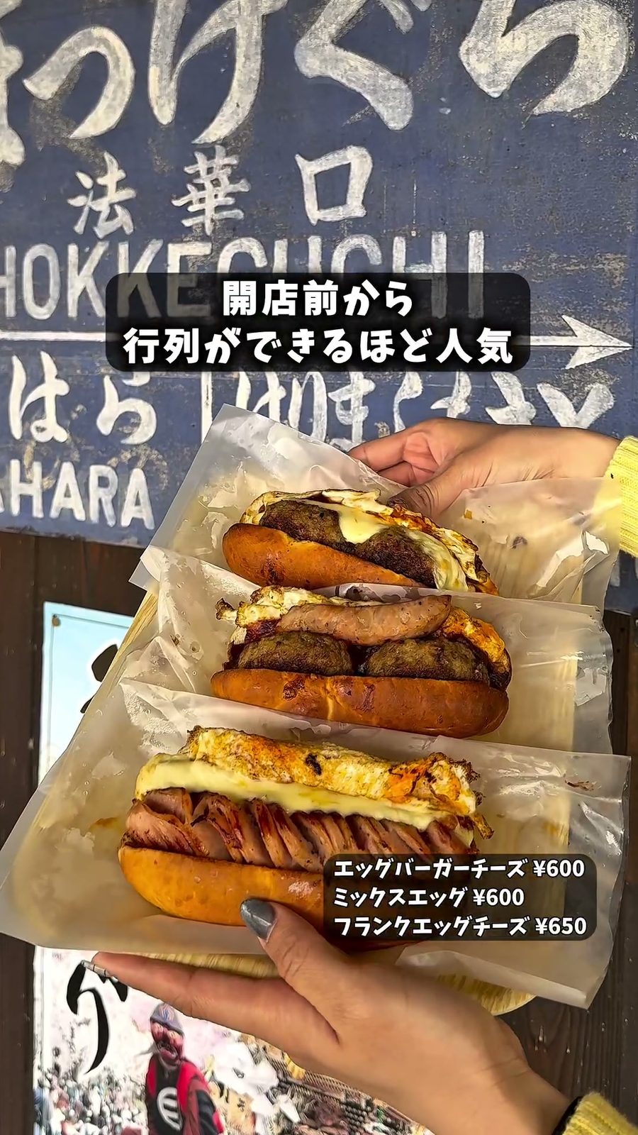 法華口駅の看板の前で手に持った3種類のハンバーガー