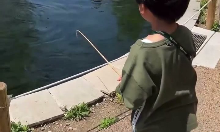 屋外の池でニジマス釣りに挑戦する子ども