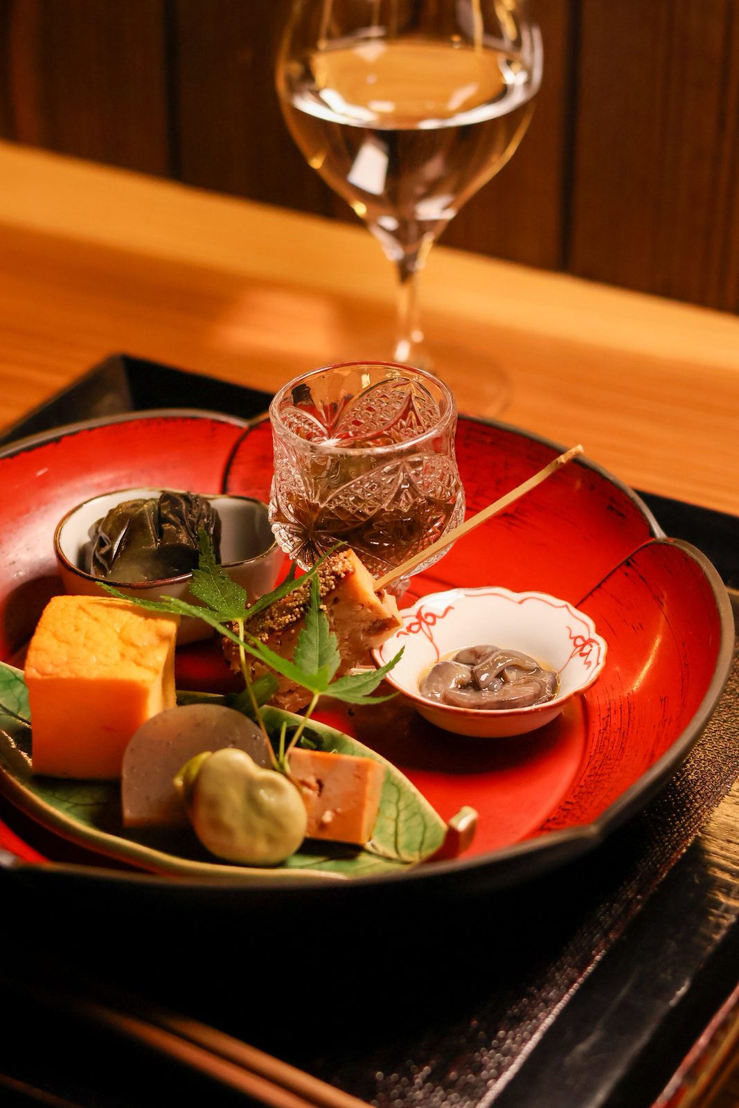 朱塗りの器に盛られた前菜の盛り合わせと日本酒