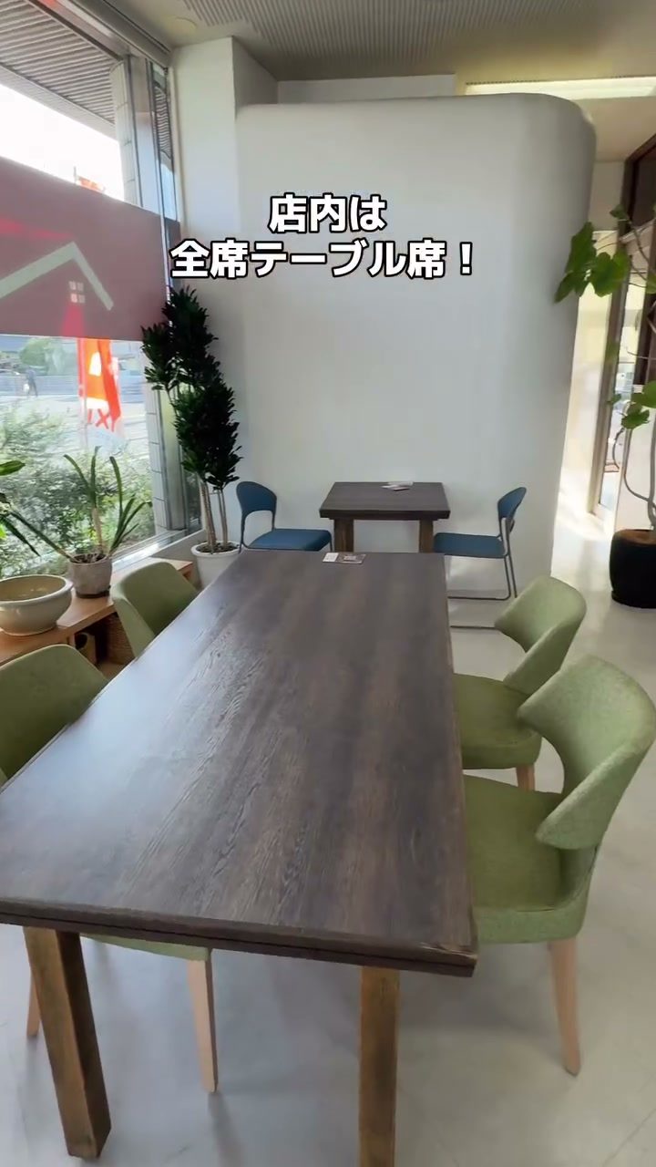 木のテーブルと緑のイスが並ぶ店内