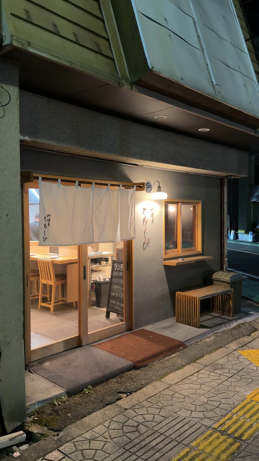 暖簾越しに灯りがもれる料理屋 ともしびの外観
