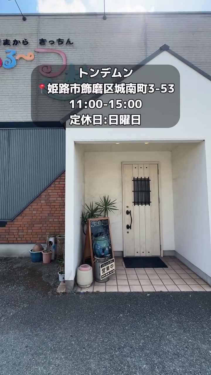 白い外壁に木のドアが映えるお店の入口