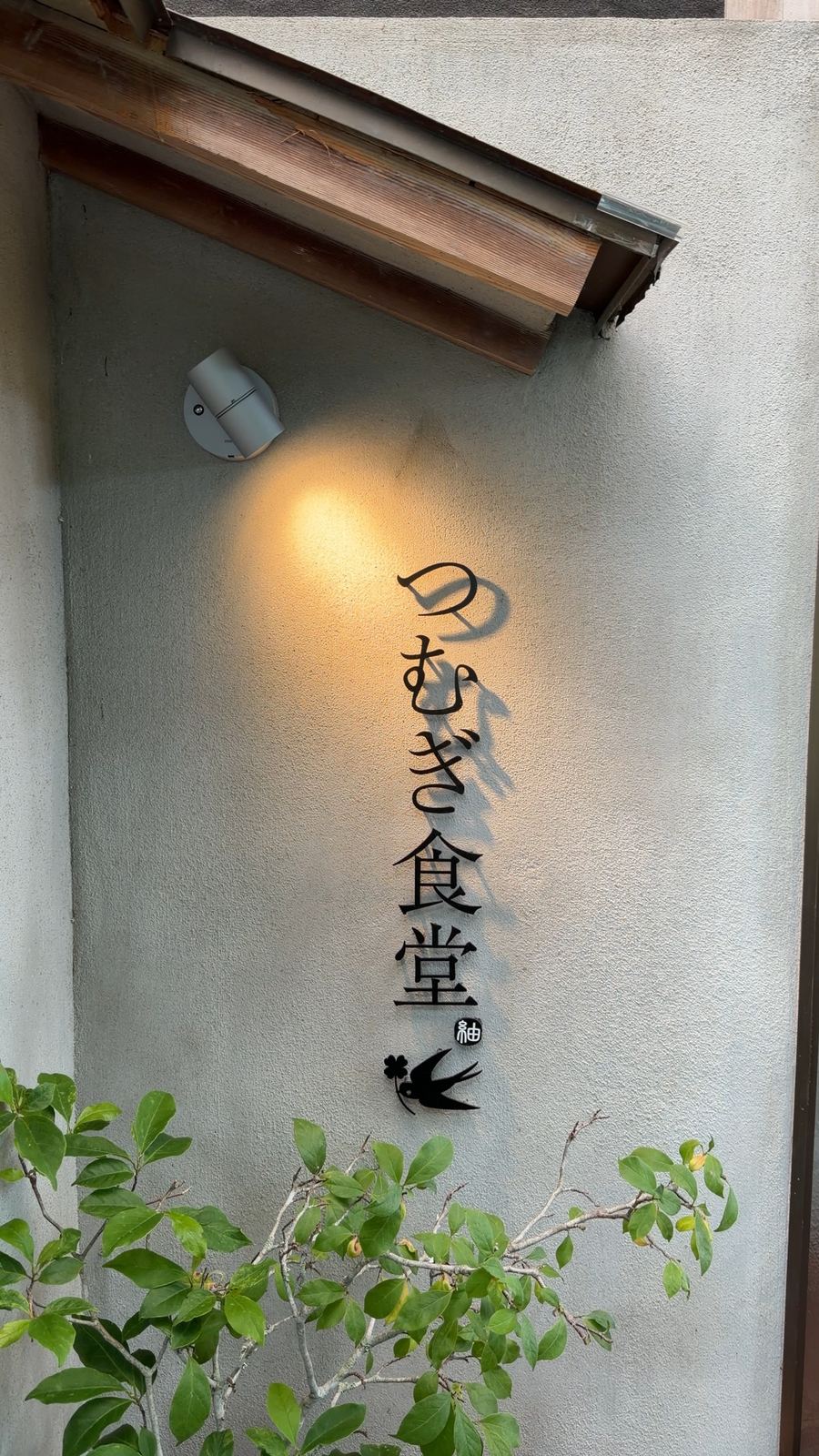 白壁に灯りがともるつむぎ食堂の表札