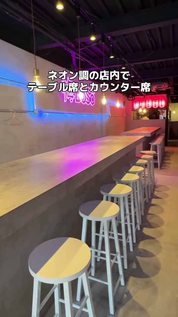 背もたれのない丸イスが並ぶネオン調のカウンター席
