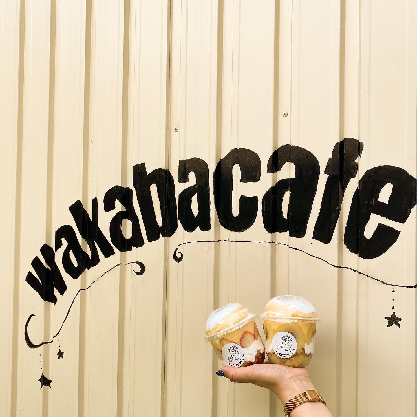 「wakabacafe」のロゴが描かれた壁とテイクアウトのカップスイーツ